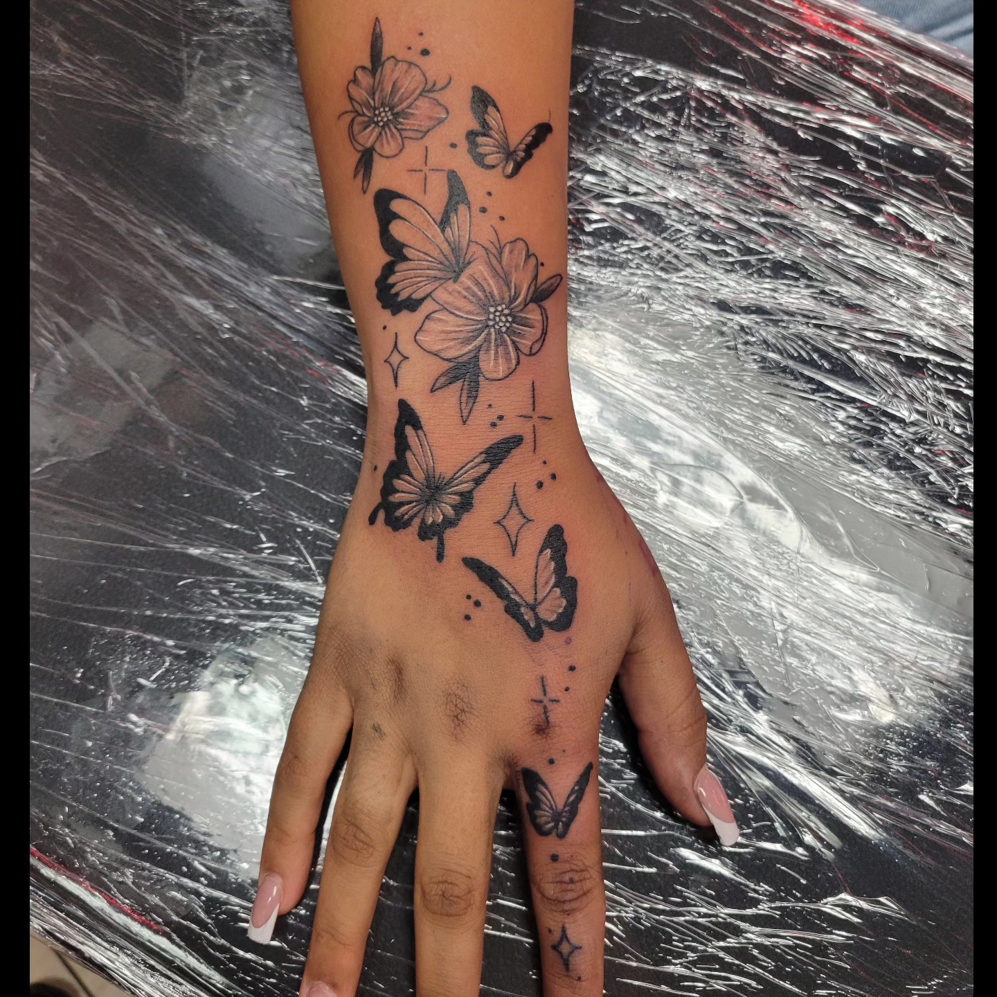 Fine line butterflies and flowers tattoo on hand and forearm