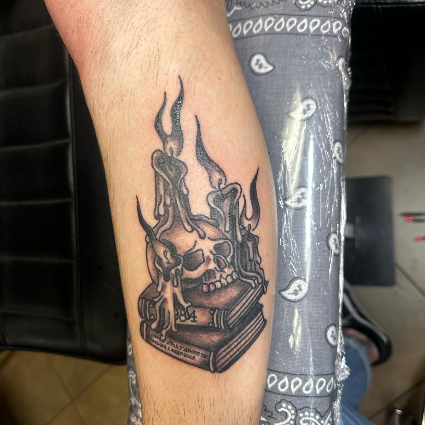 Black and grey skull with candles and books tattoo on calf