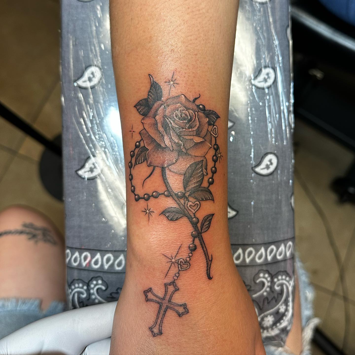 Black and grey rose with rosary and cross tattoo on wrist