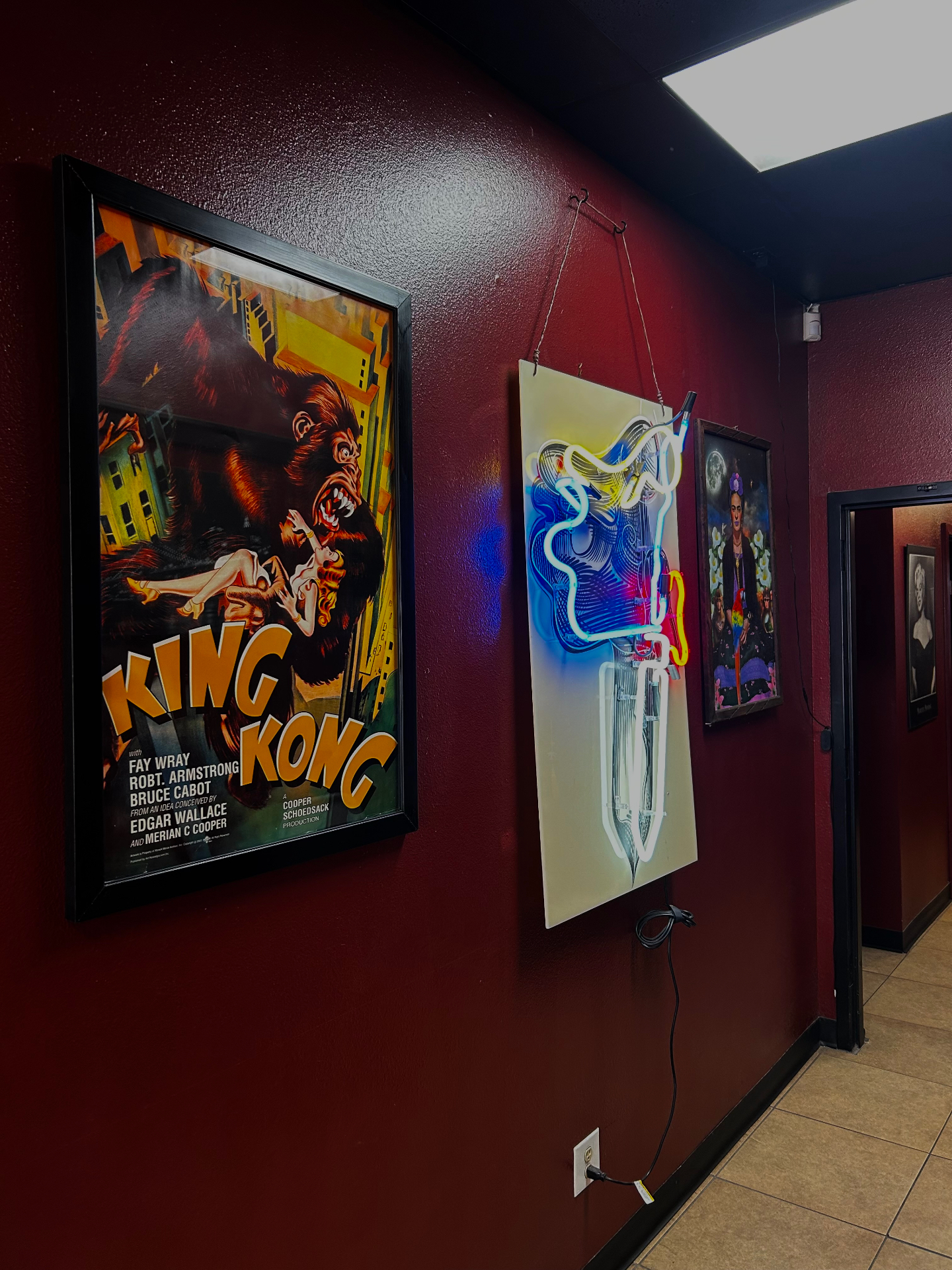 Studio hallway with framed artwork on deep maroon walls