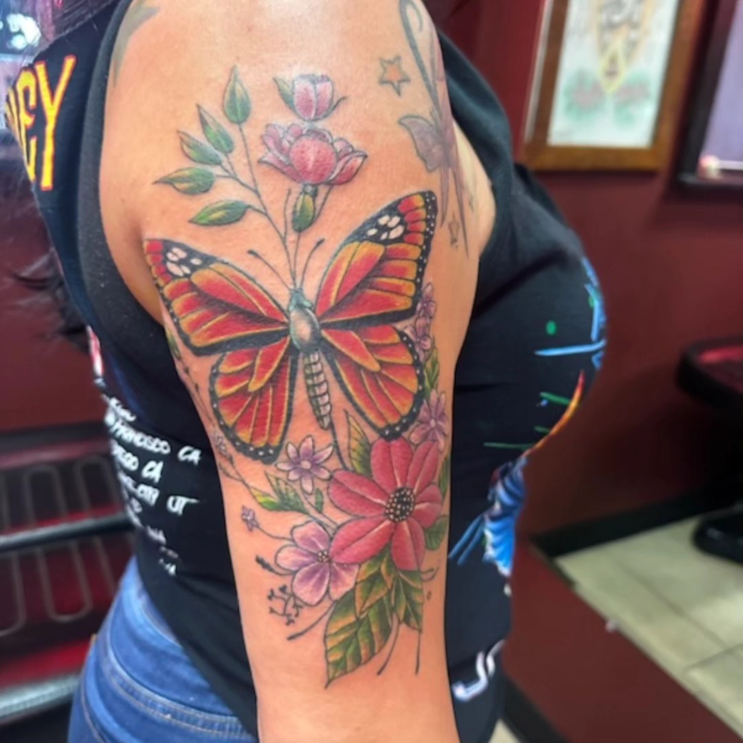 Color monarch butterfly and wildflowers tattoo on upper arm