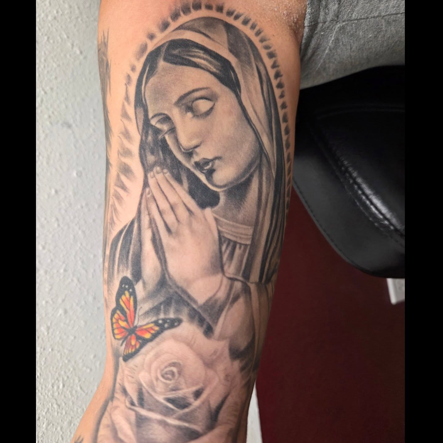 Black and grey praying Virgin Mary with monarch butterfly arm tattoo