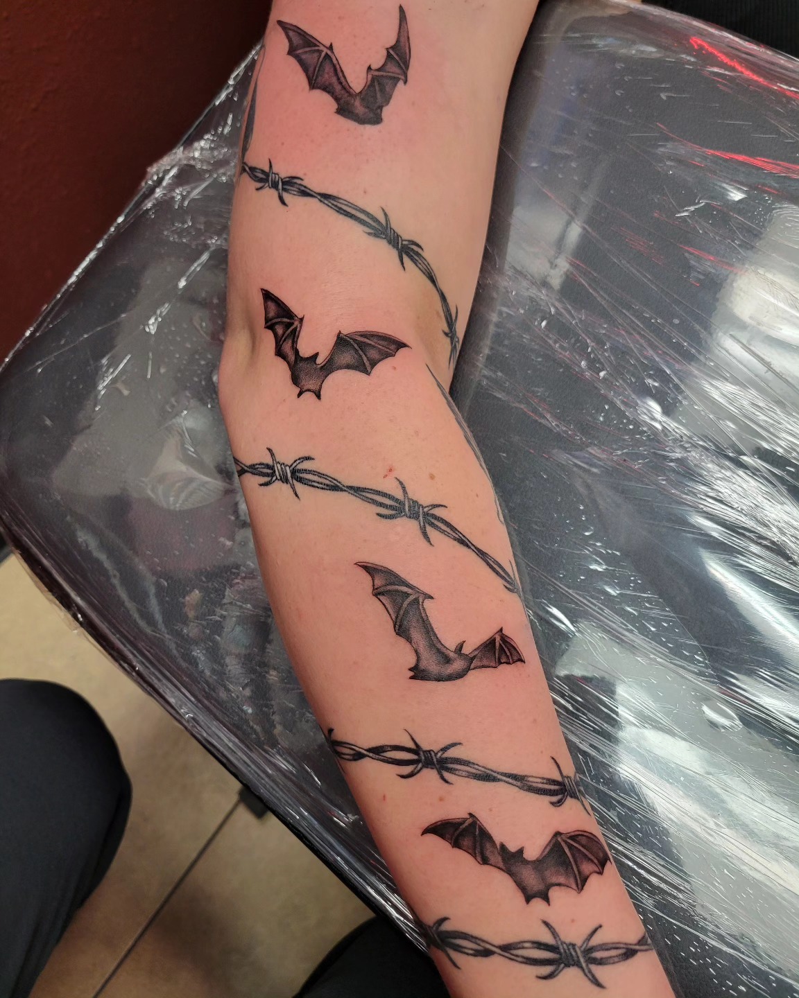 Black and grey bats and barbed wire sleeve tattoo
