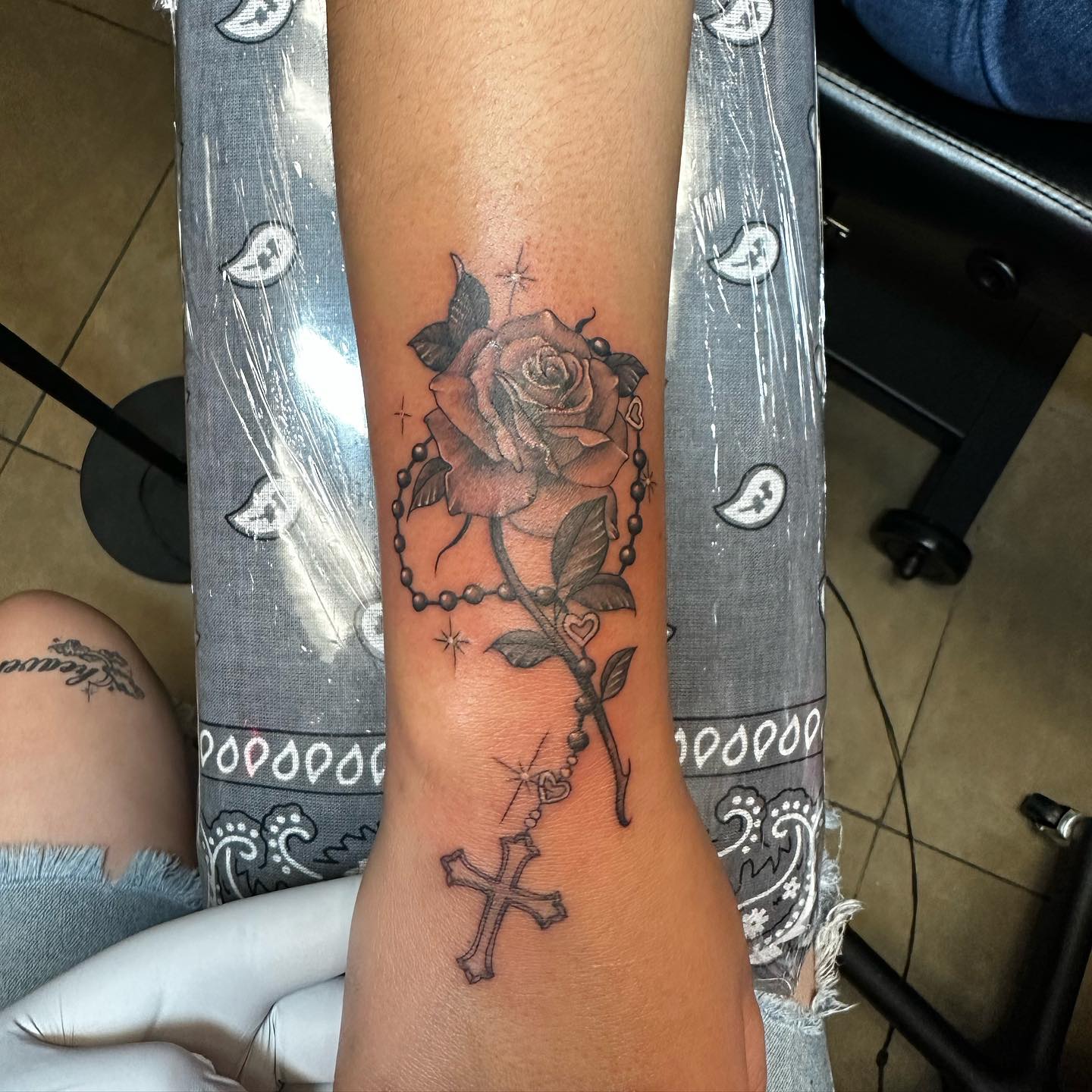 Black and grey rose with rosary beads and cross forearm tattoo
