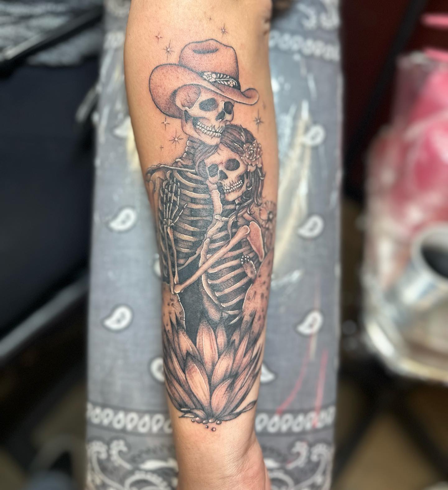 Black and grey cowboy and lady skeleton embrace tattoo on forearm