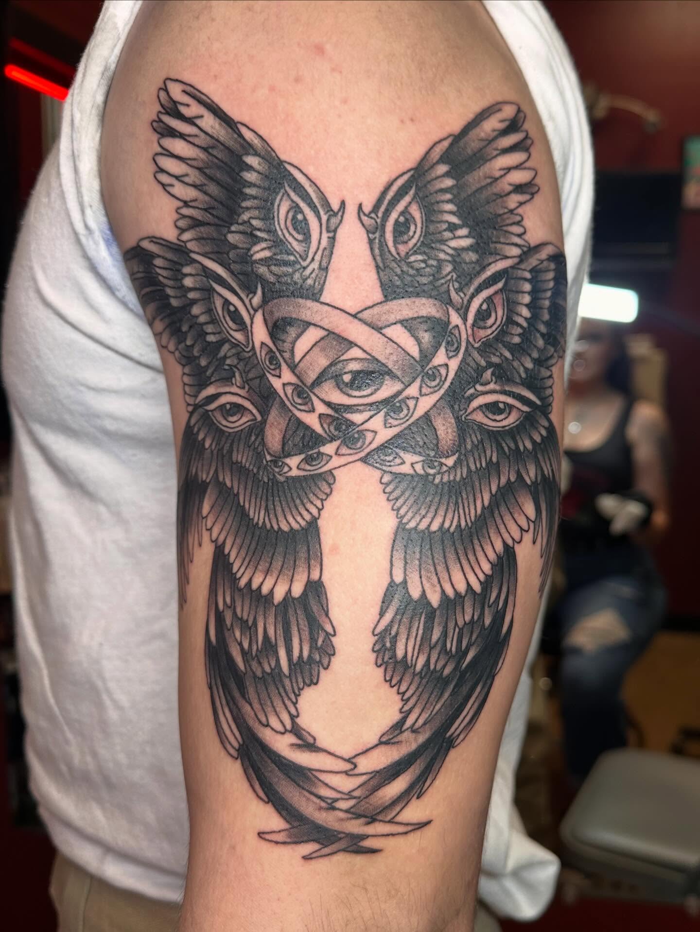 Black and grey winged owl with multi-eye composition tattoo on upper arm